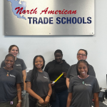 NATS women staff and students smiling in front of indoor signage