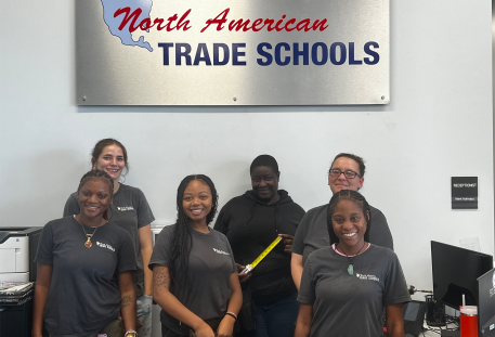 NATS women staff and students smiling in front of indoor signage
