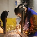 welder wearing ppe working on a metal pipe