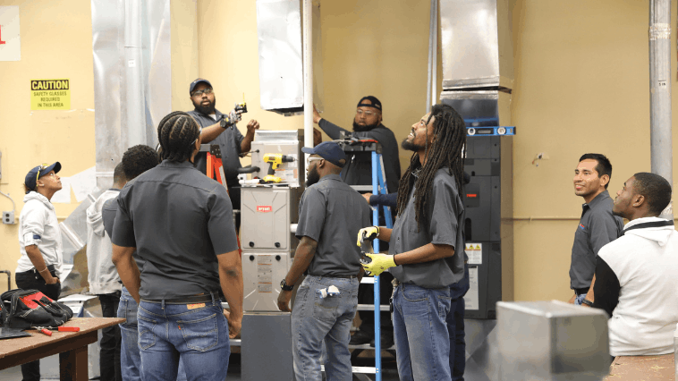 Group of HVAC students and instructors gathered around HVAC equipment