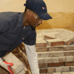 NATS student grabbing bricks from a large pile
