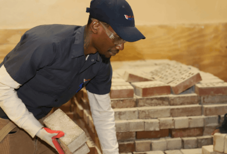 NATS student grabbing bricks from a large pile