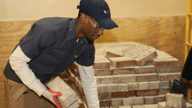 NATS student grabbing bricks from a large pile