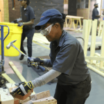 Construction student hammering a pile of bricks