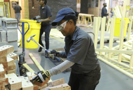 Construction student hammering a pile of bricks