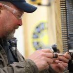 Trade school student wearing safety glasses working on an electrical component during electrician training