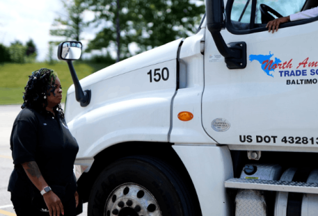 Closeup of NATS white semi truck cab with instructor standing in front