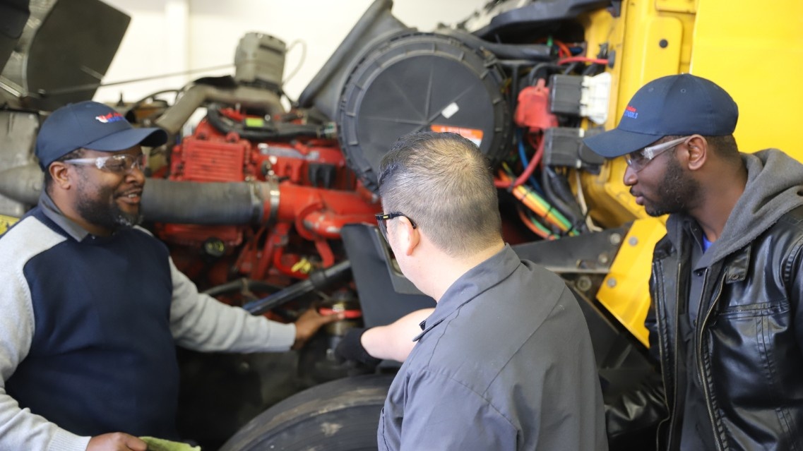 Students and instructors working on semi truck engine
